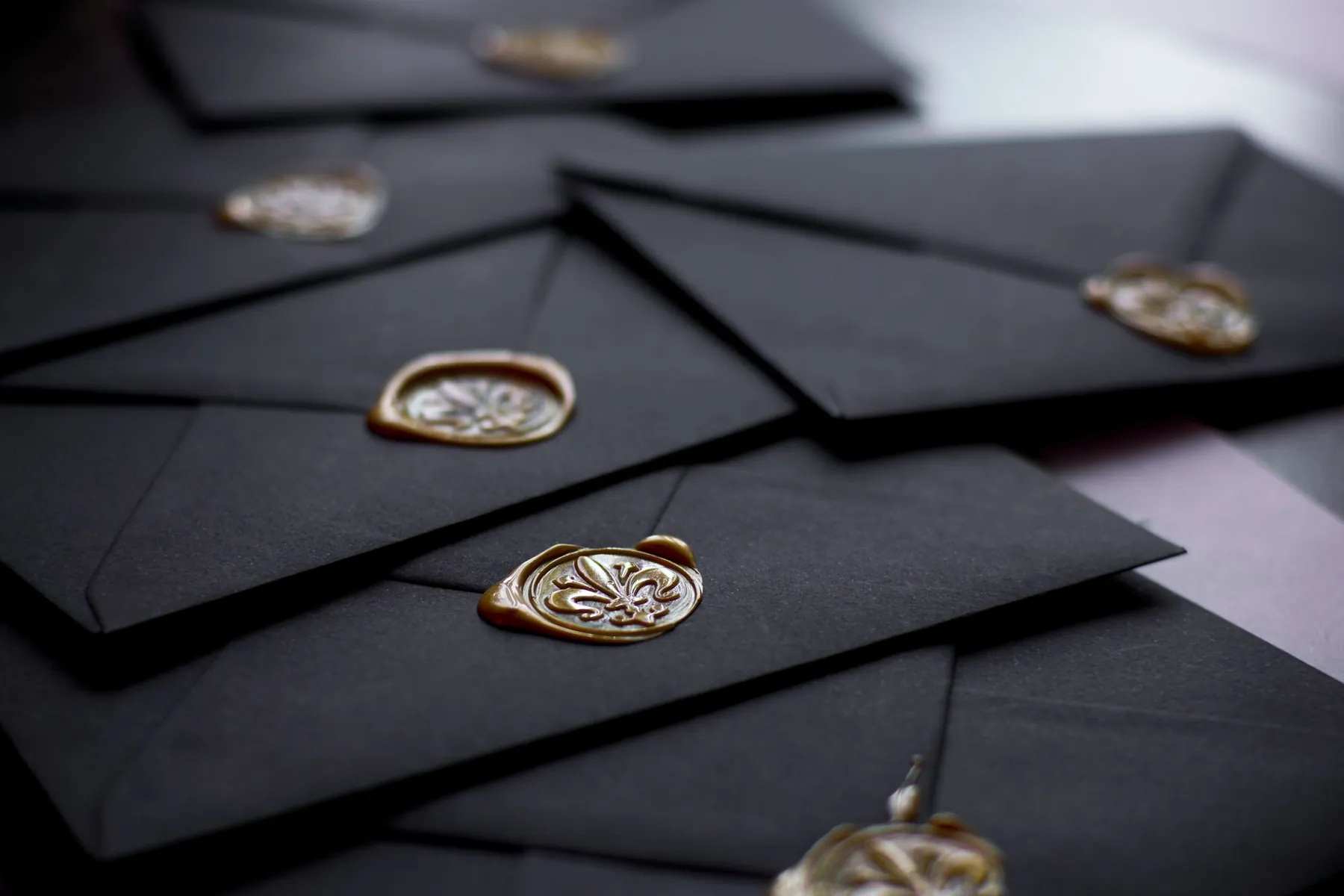 Black envelopes closed with gold wax seals.