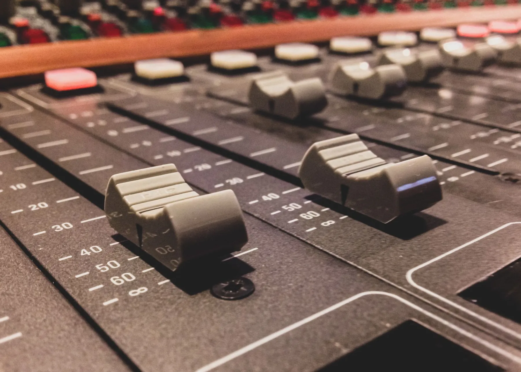 Close-up of mixing console faders in warm light.