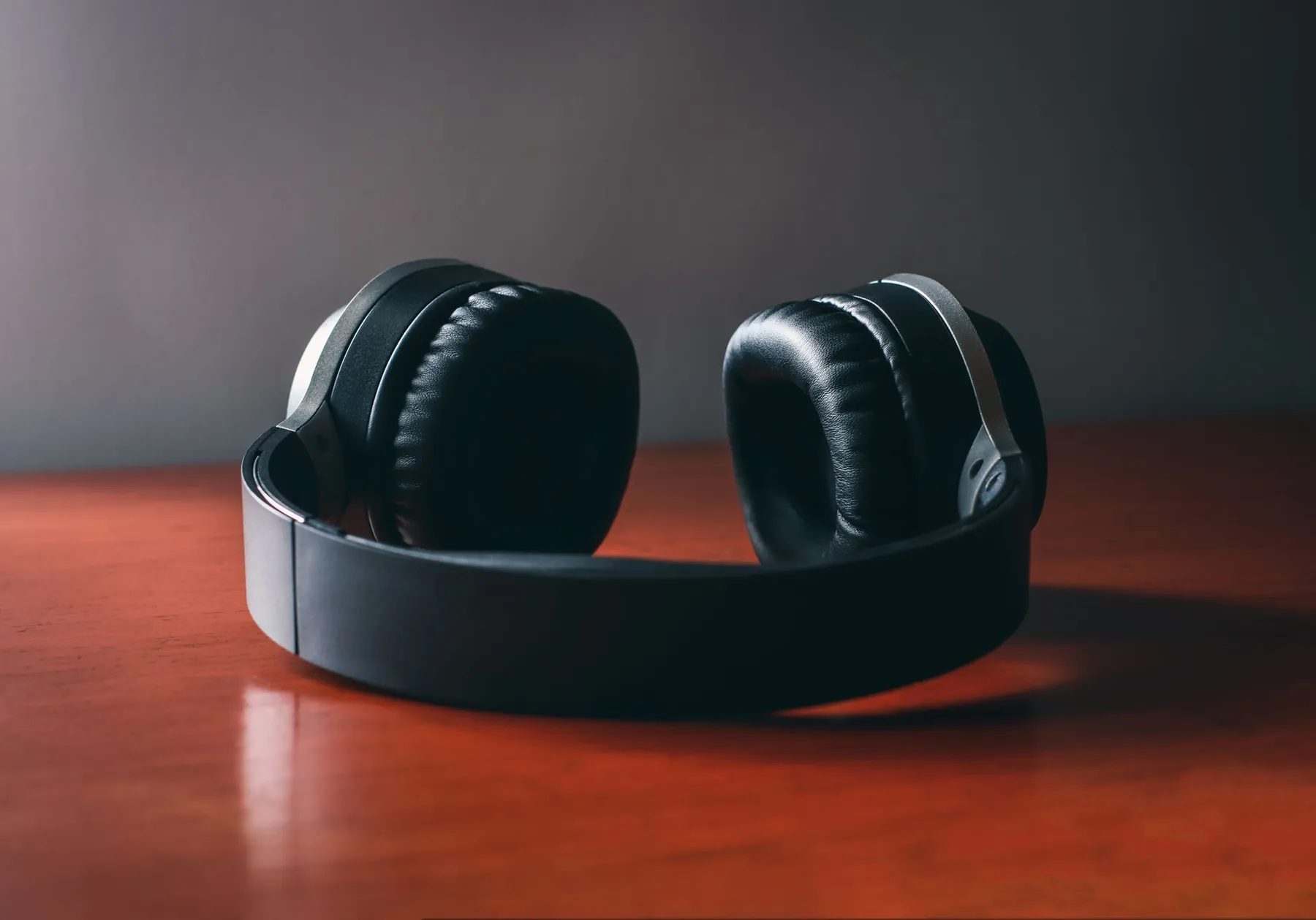 Over-ear headphones resting on a polished wooden table.