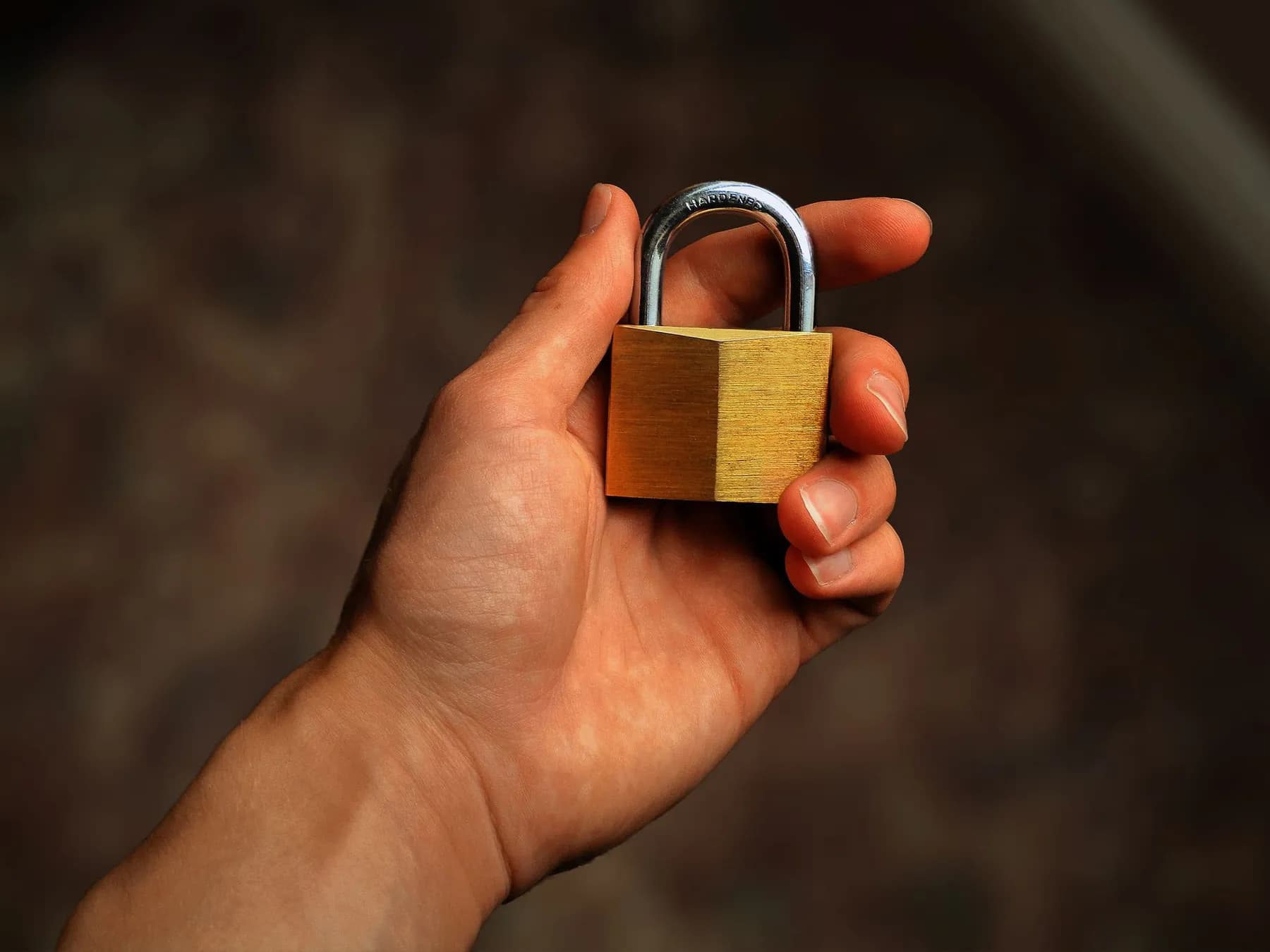 A hand holding a brass padlock.